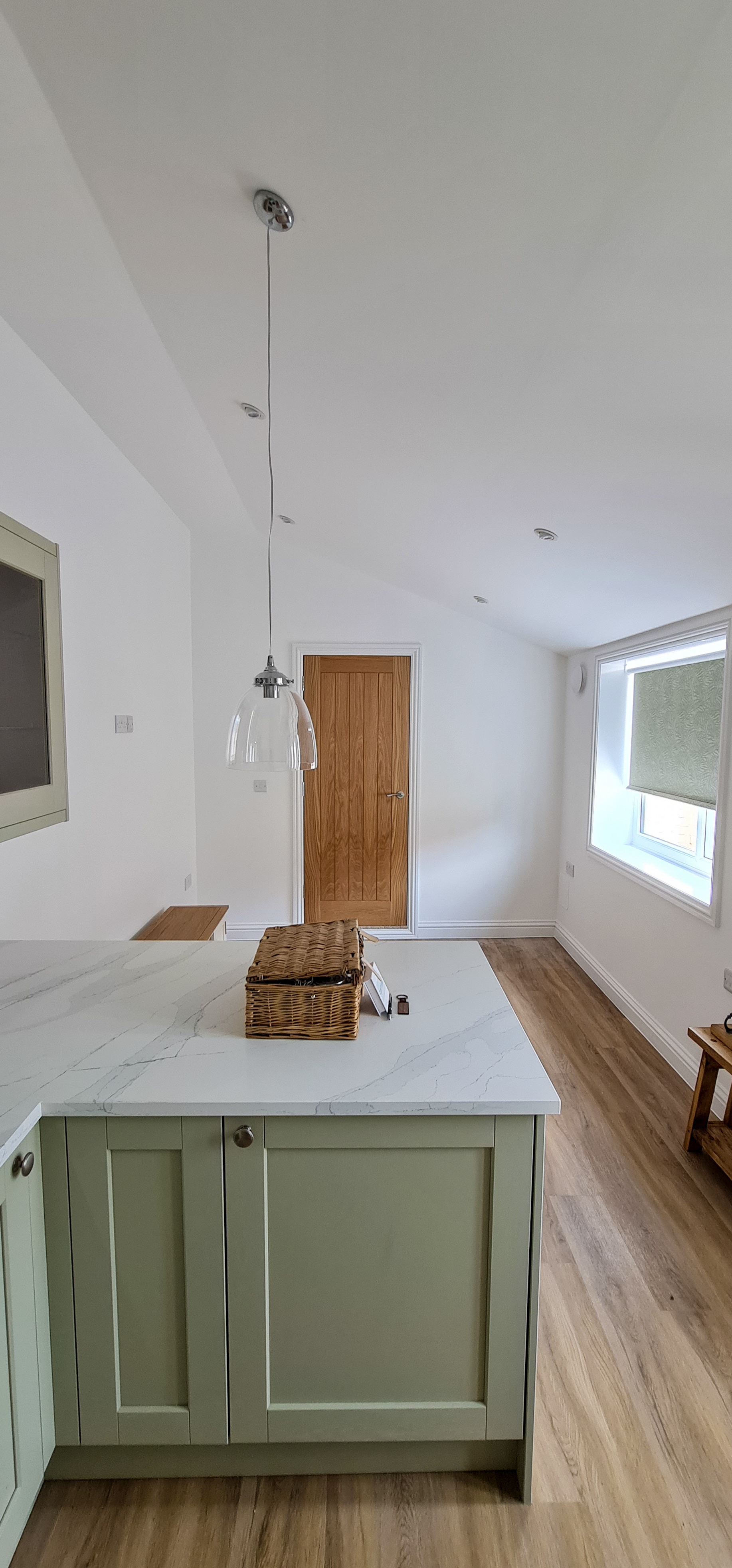 Open-plan kitchen with sage green units and a marble-topped island