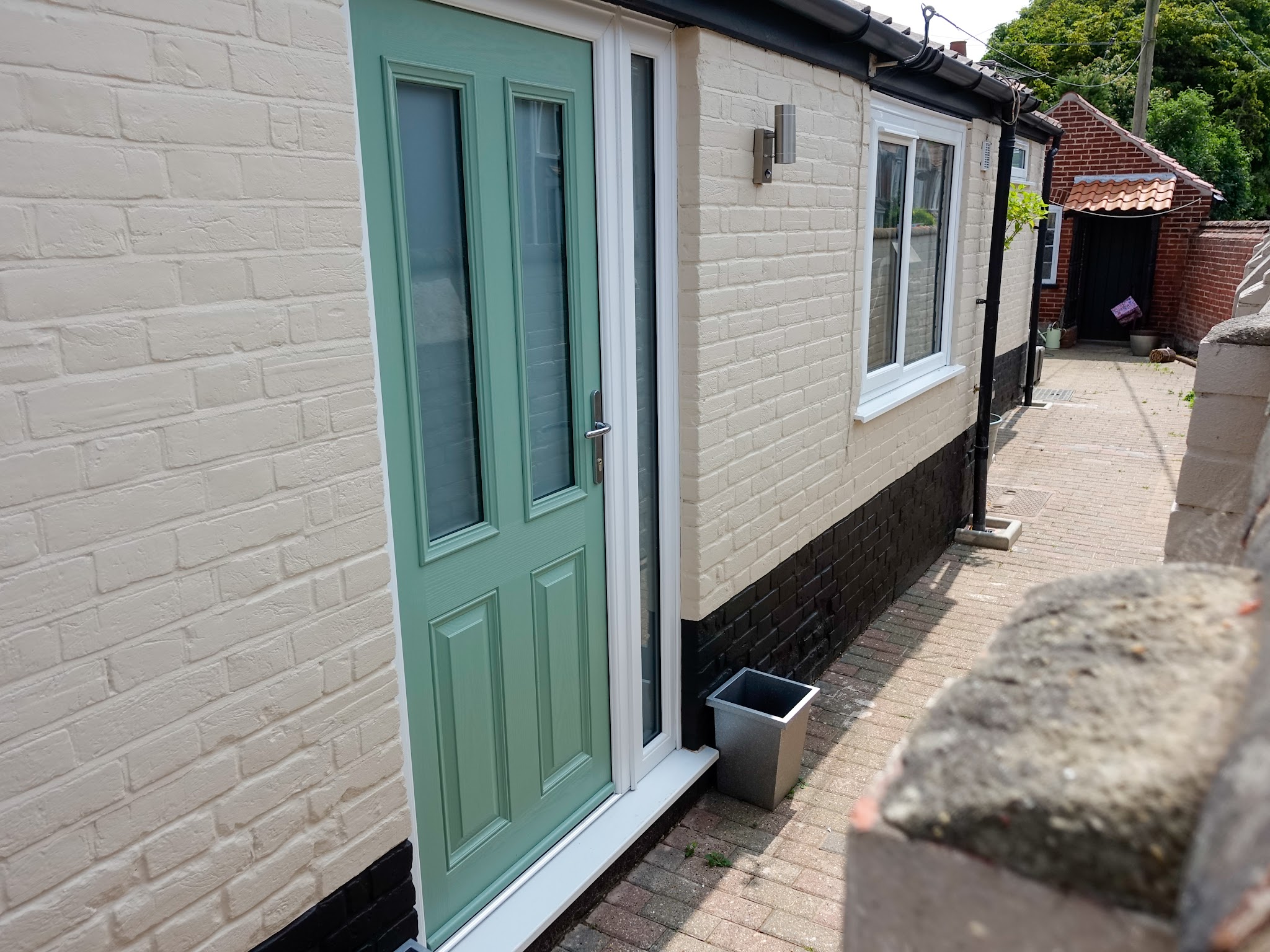 Painted brick cottage wall with a green front door